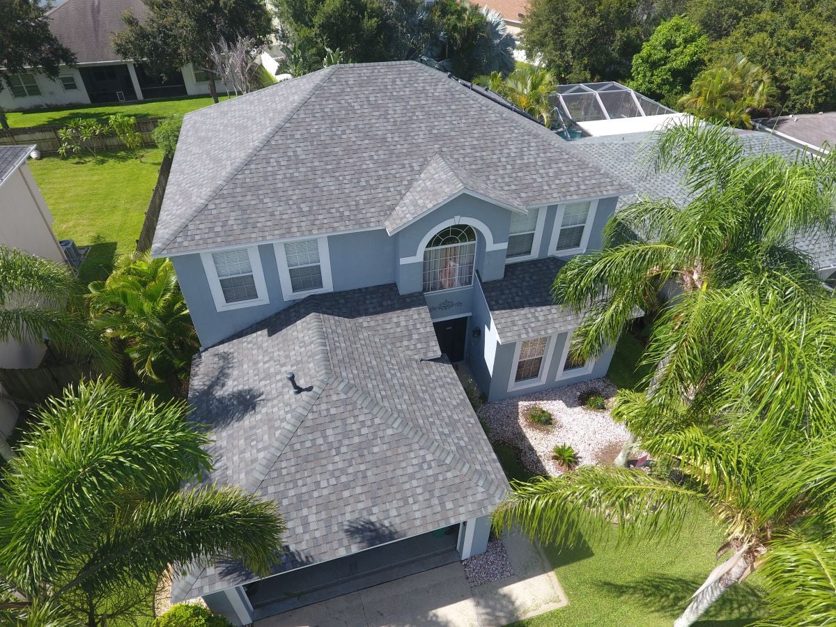 Residential roofing grey roof big house surrounded by palms in Florida