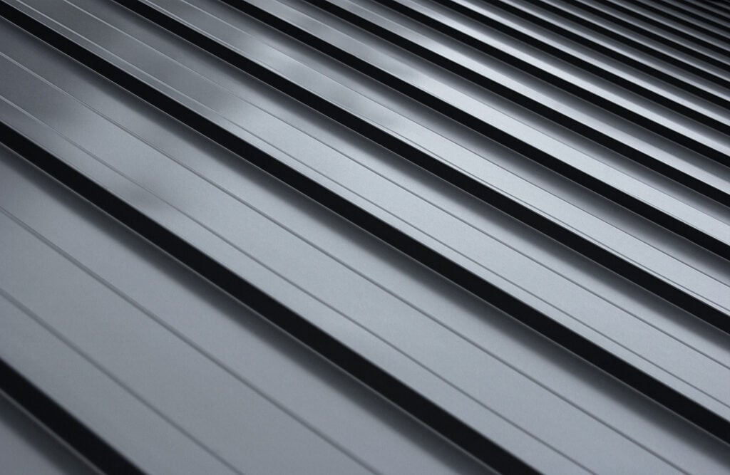 Close-up house metal roof panel with standing seam and fasteners.