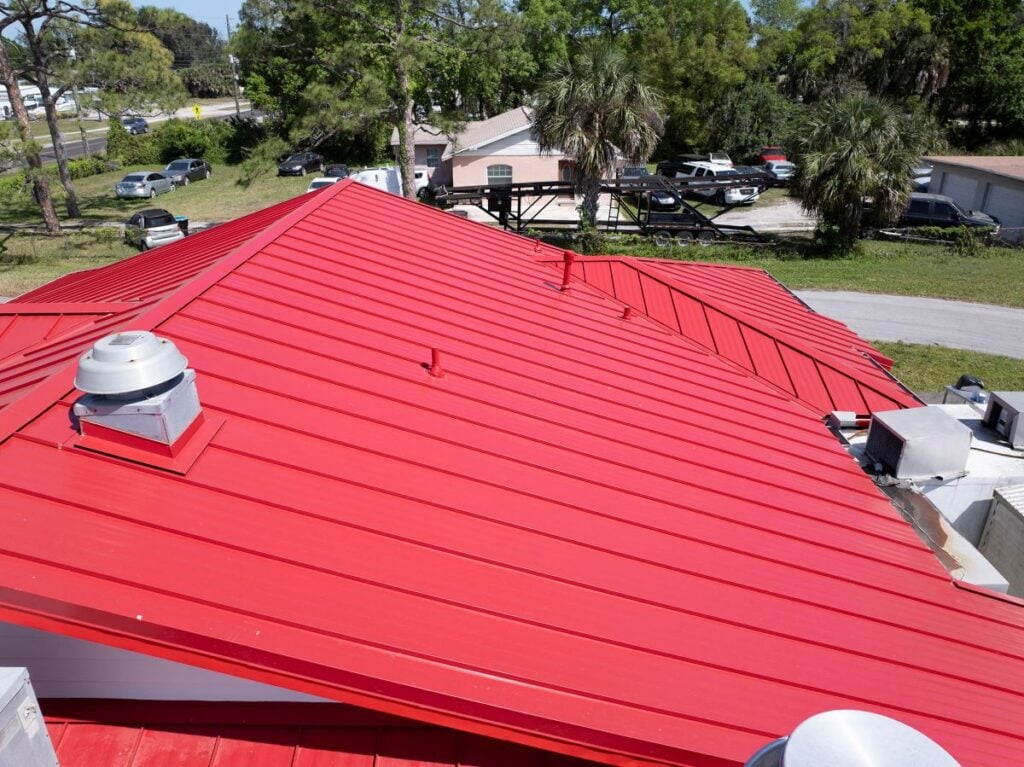 red metal roof leak repair big house sunny day cars on street vents Florida Roof Bros project
