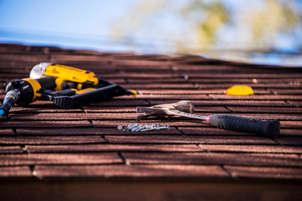 roofing tools hammer and nail gun laying on top of roof