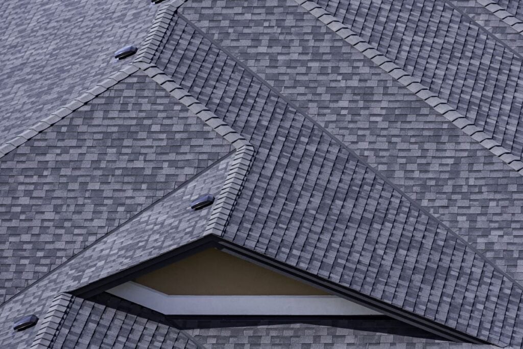 Asphalt shingle roofing in grey tones, showcasing a complex roof design with multiple slopes and angles, relevant to roofing cost estimates for homeowners in Melbourne Beach, FL.