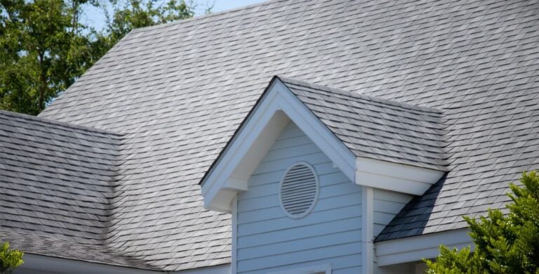 Asphalt shingle roofing on a modern house in Florida, showcasing durability and weather resistance, with a gable vent and grey tones suitable for the local climate.