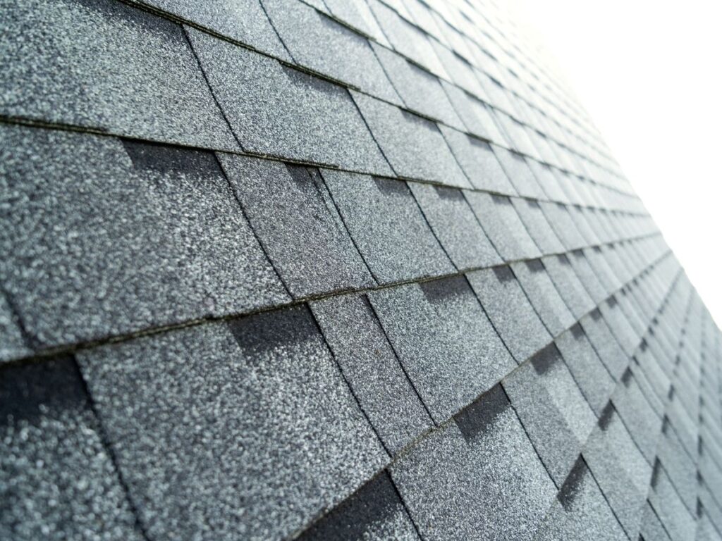 Close-up of grey asphalt shingles, showcasing texture and alignment, relevant to roofing material choices and cost considerations for homeowners.